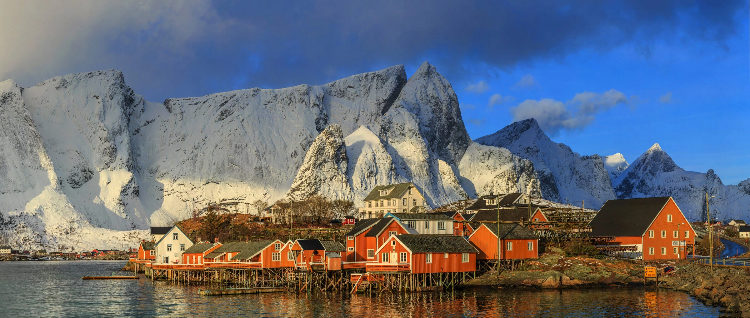 Red fishermen's cabins on the water below snow-covered Lofoten peaks